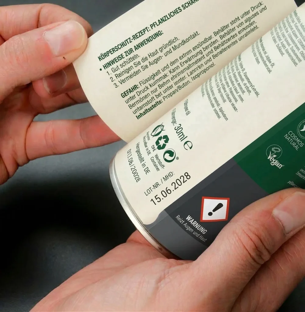 Hände klappen Mehrlagen-Etikett auf Spraydose auf und zeigen Inhaltsstoffe und GHS-Warnung